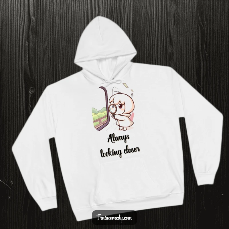 Funny hoodie depicting a curious character with a magnifying glass pressed against a train window, examining the outside view.